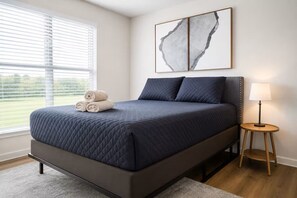 A modern bedroom with a bed, a bedside table, a lamp, and artwork on the wall. - Stunning 1BR near @ TheHeights w/ BBQ, Gym+Pool (Houston)