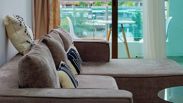 Ein modernes Wohnzimmer mit Sofa, Glastisch und Blick auf Pool und Grünfläche.