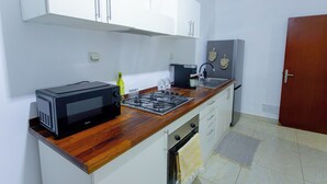 Uma cozinha com armários brancos, micro-ondas, fogão a gás e geladeira.