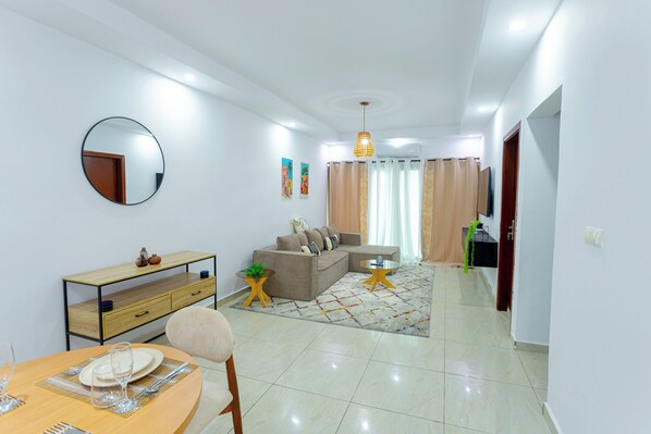 Una sala moderna con comedor, un sofá, una mesa de centro y un televisor.