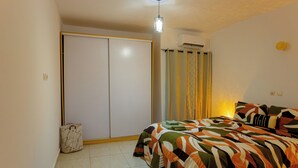 Ein Schlafzimmer mit einem Bett, einem Kleiderschrank, einem Koffer und einer Deckenleuchte.