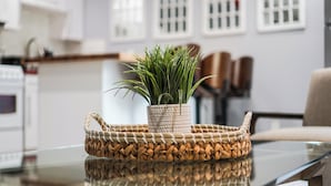 A woven basket with a potted plant on a glass table in a modern kitchen. - Cozy 2-bedroom condo in peaceful studio city with AC (Burbank)