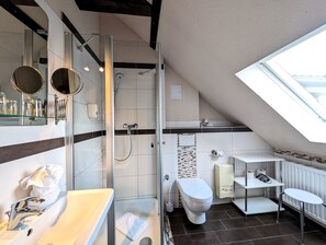 A modern bathroom with a glass shower enclosure, a white sink, a toilet, and a small table. - Hotel Altstadtperle Erfurt (Erfurt)
