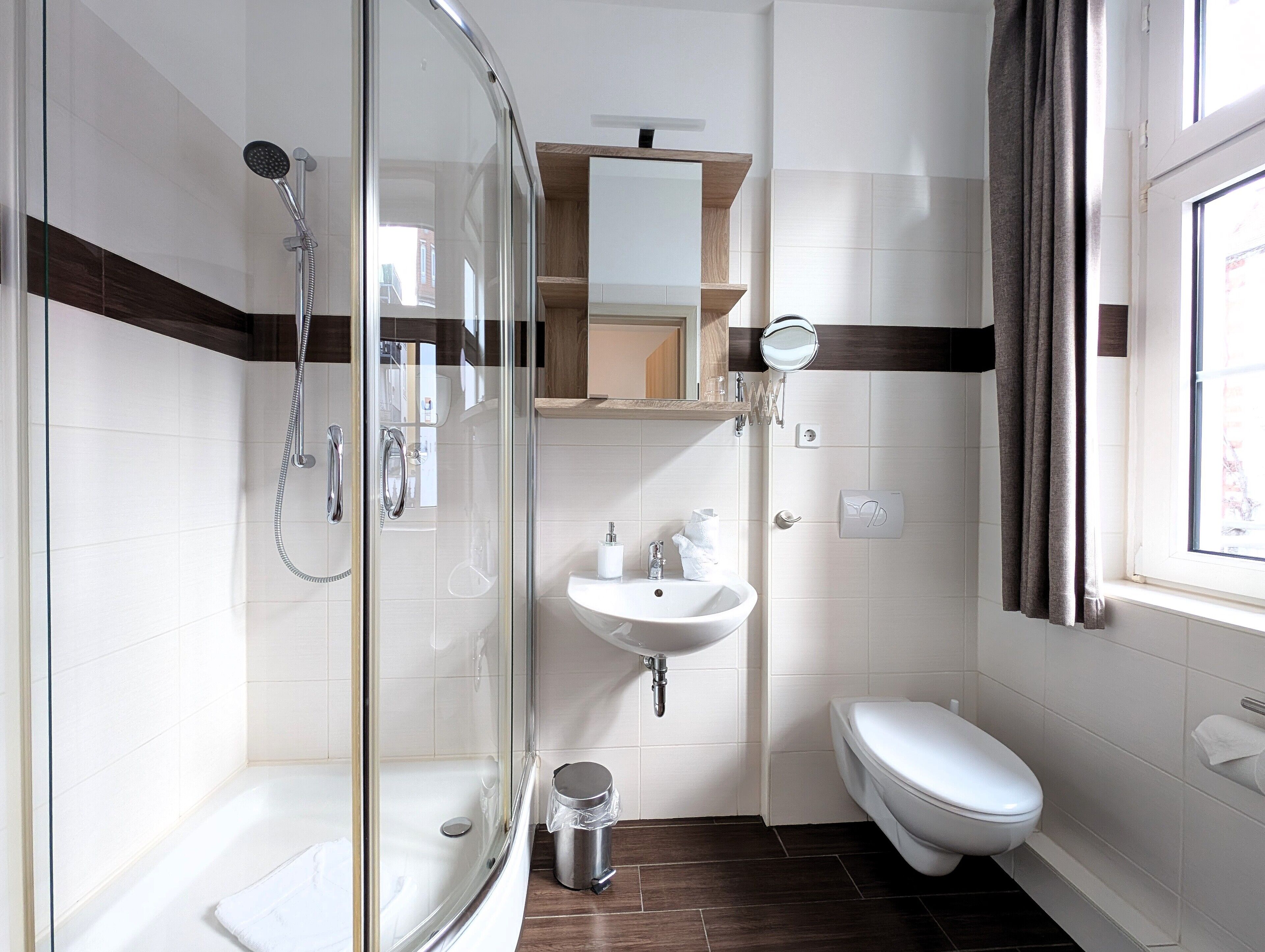 Ein modernes Badezimmer mit Duschkabine aus Glas, Waschbecken und Toilette.