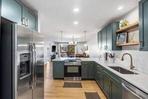 A modern kitchen with stainless steel appliances, teal cabinetry, and a central island. - Avondale Hideaway Condo for 6 (Branson)