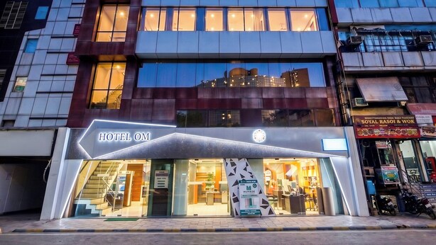 A modern hotel with a glass facade, a visible reception area, and a sign indicating it is a hotel. - Hotel om international  (New Delhi)