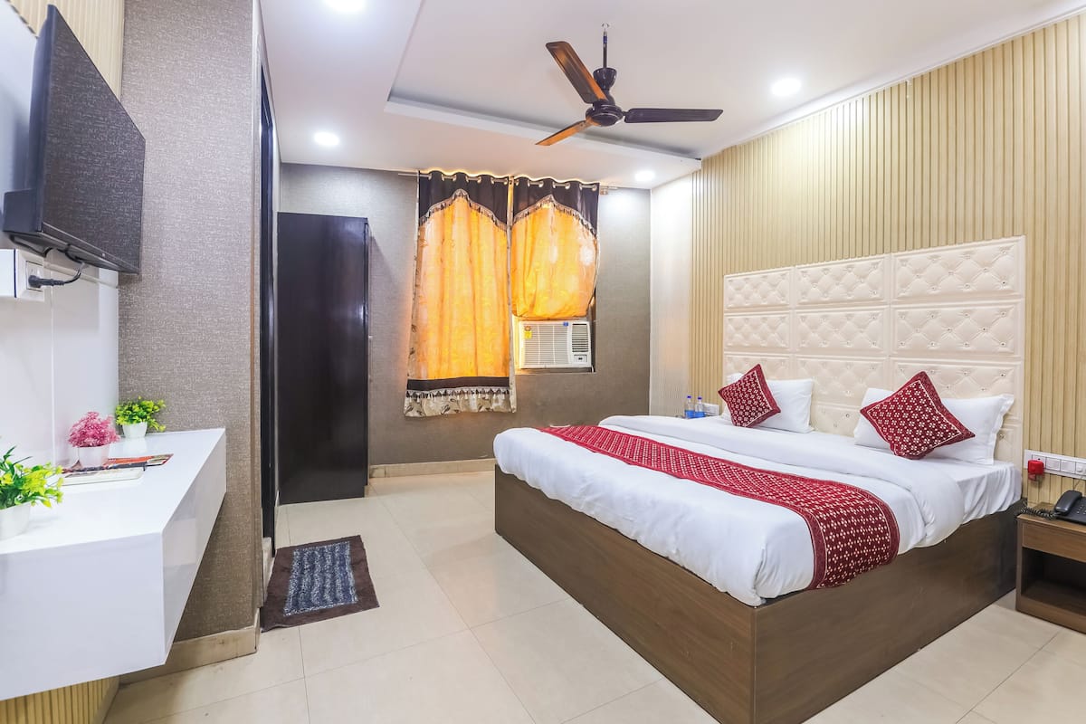 A hotel room with a bed, bedside table, desk, and a ceiling fan.