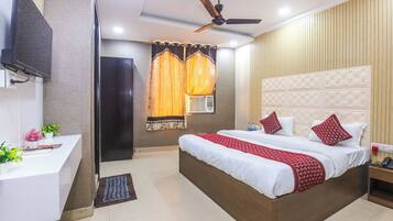A hotel room with a bed, bedside table, desk, and a ceiling fan.