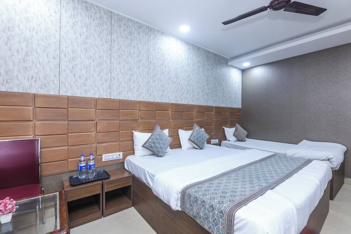 A hotel room with a large bed, a wooden headboard, a TV, a desk, and a ceiling fan.
