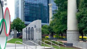 A large Olympic rings sculpture and a stone monument with the number 100. - Walk to the 2026 FIFA games! (Atlanta)