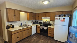 A compact kitchen with wooden cabinets, a dishwasher, a stove, and a refrigerator. - 3-bedroom house in lancaster. (Lancaster)