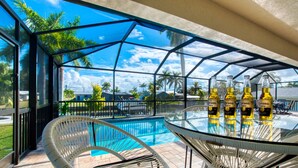 A glass-enclosed outdoor area with a pool, chairs, and bottles of Corona Extra. - Villa Sunny Dream - New Villa - perfect for families and boaters (Cape Coral)