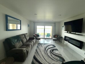 A living room with a sofa, a television, and a view to the outside. - Beautiful Waterfront Sunsets! (St. Augustine)
