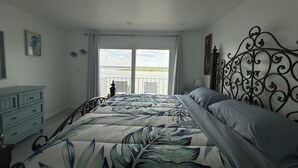Een slaapkamer met een bed, een kast en uitzicht op het water.