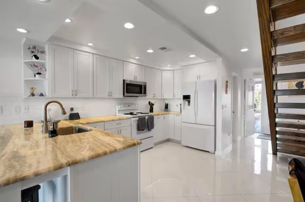 A modern kitchen with white cabinetry, a wooden countertop, and stainless steel appliances.