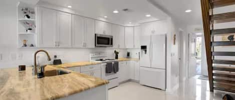A modern kitchen with white cabinetry, a wooden countertop, and stainless steel appliances.
