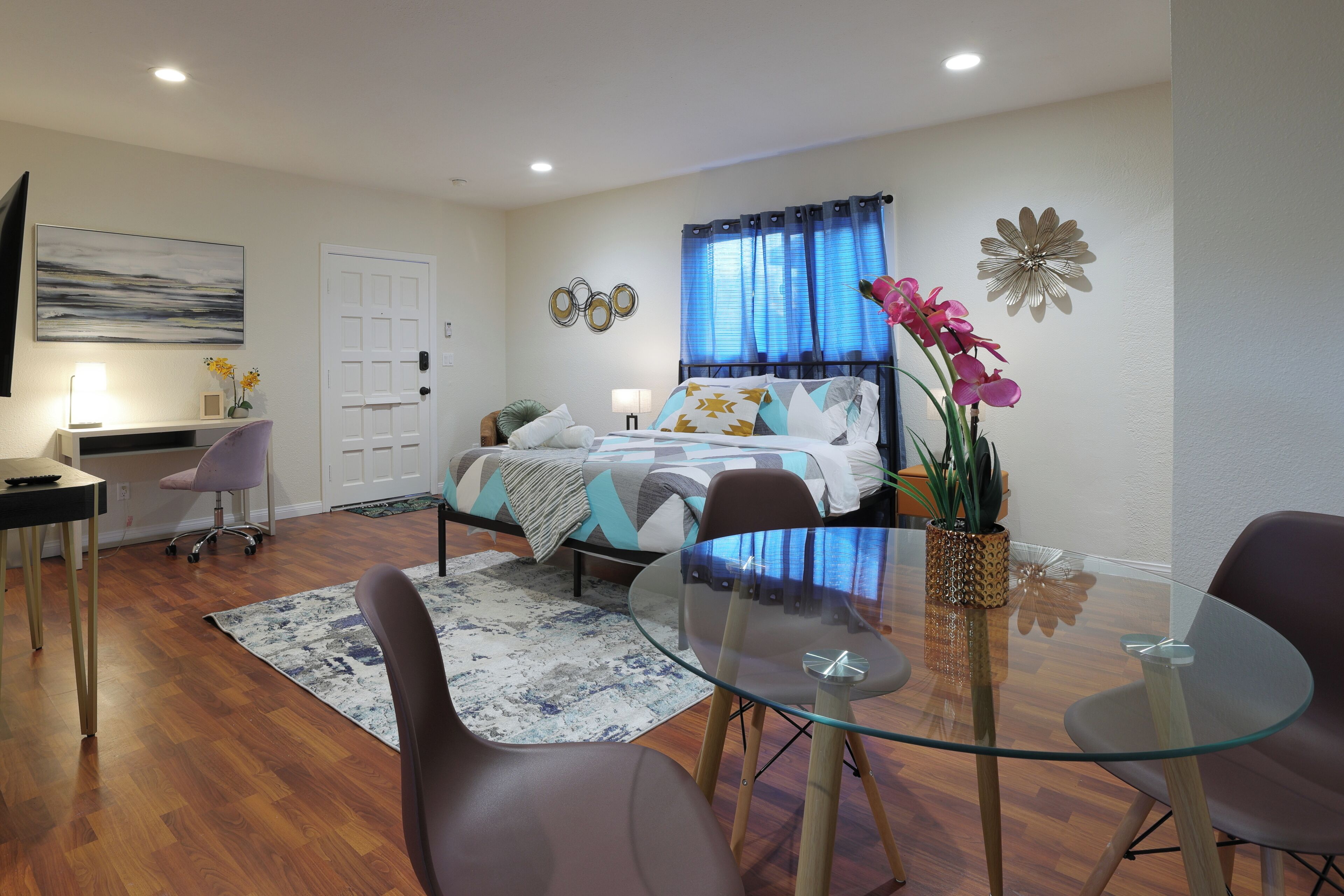 Une chambre à coucher moderne, avec un lit, une table de chevet, une lampe et une table en verre avec des chaises.