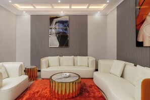 Un moderno salón con un sofá blanco, una mesa de centro redonda y un tapete rojo.