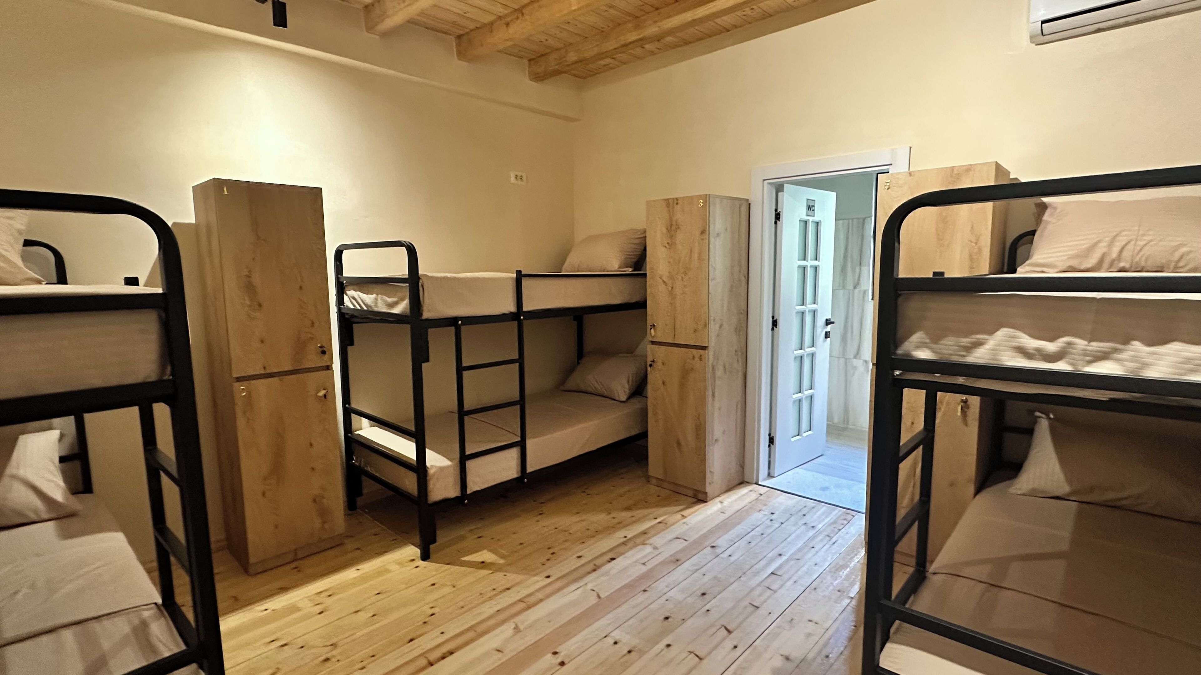 Une pièce avec des lits superposés, un plancher en bois et une porte donnant sur une autre pièce.