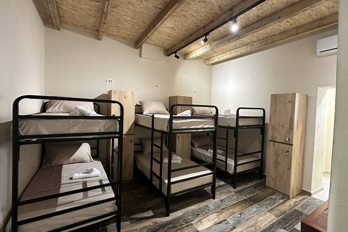 Bunk beds with wooden frames, a wardrobe, and an air conditioning unit in a room with a wooden ceiling.