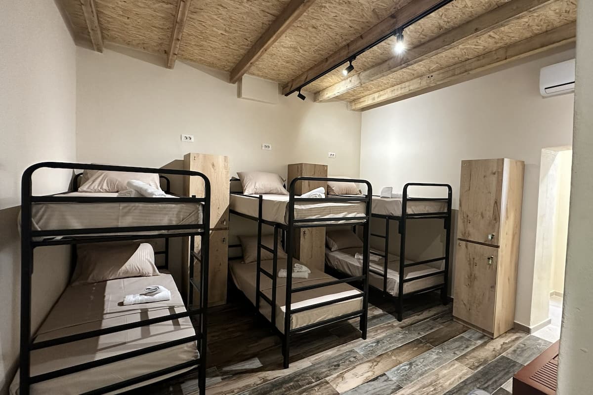 Bunk beds with wooden frames, a wardrobe, and an air conditioning unit in a room with a wooden ceiling.