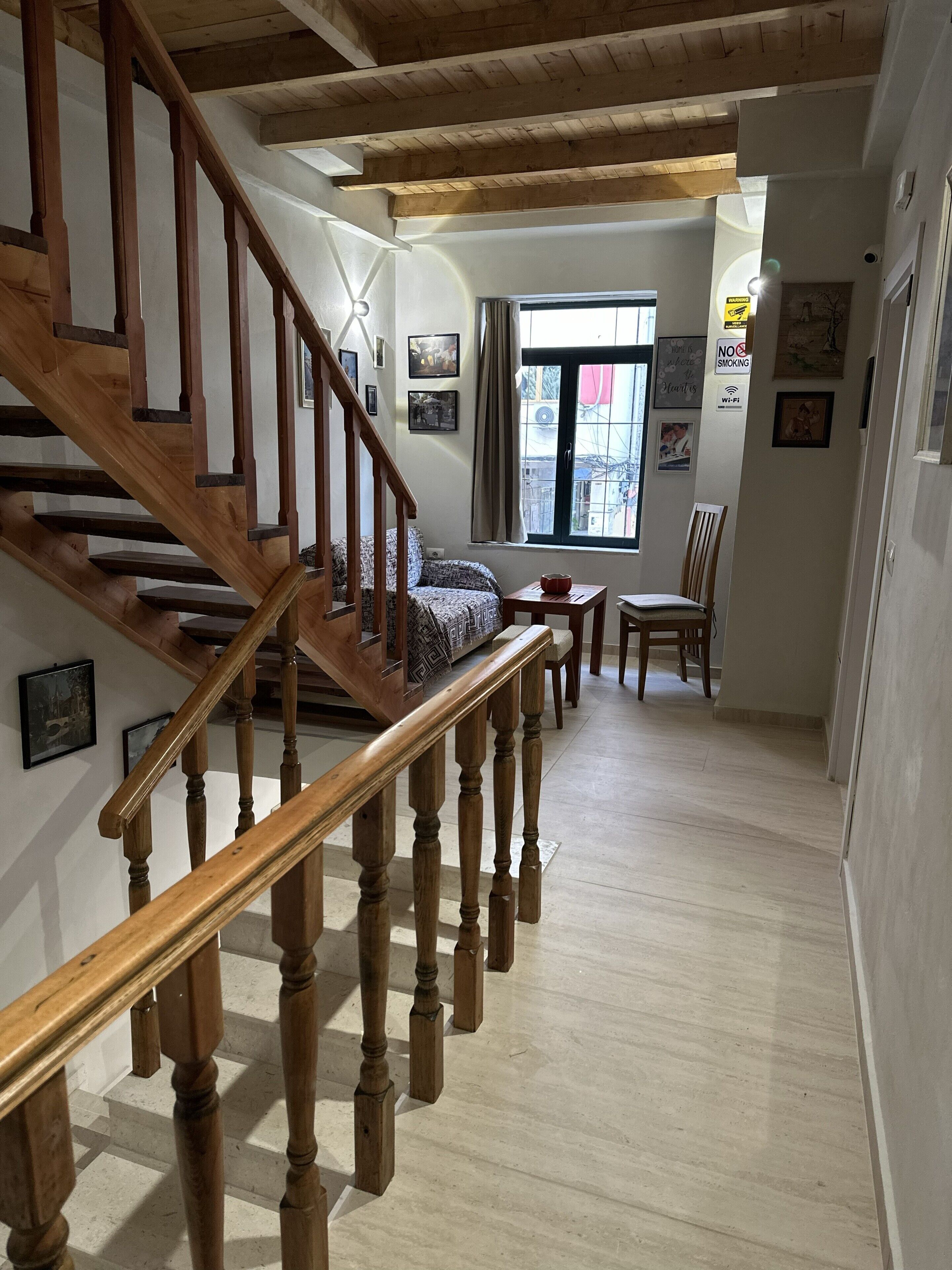 A wooden staircase leading to a living area with a sofa, a dining table, and chairs.