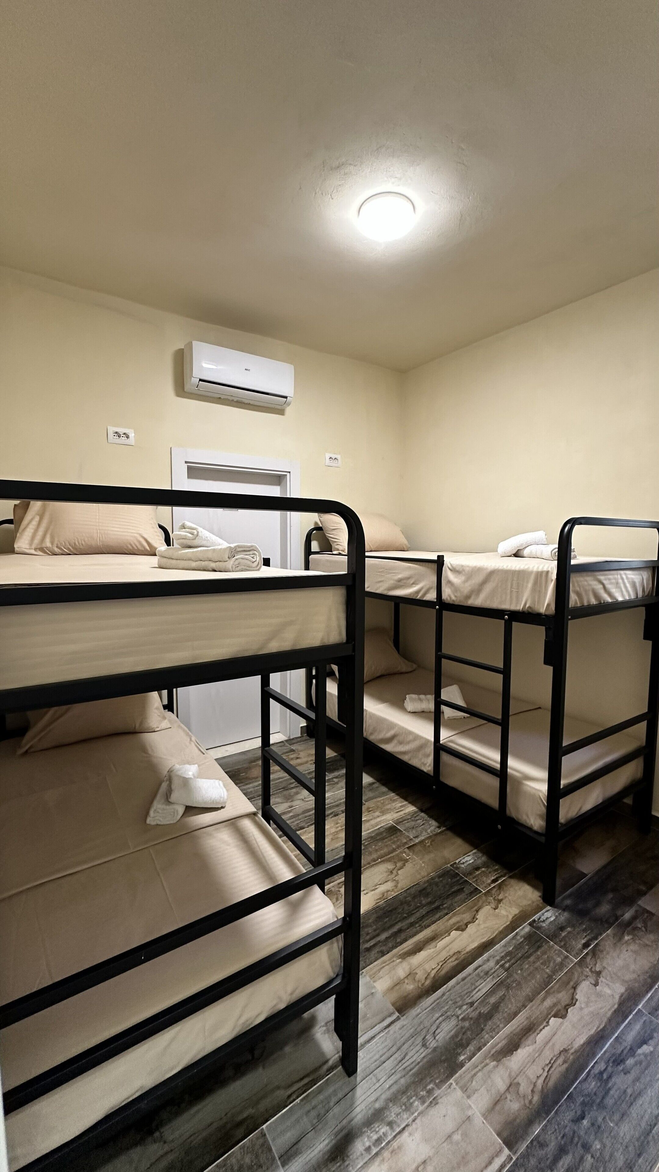 Une chambre avec des lits superposés, un luminaire au plafond et un appareil de climatisation.
