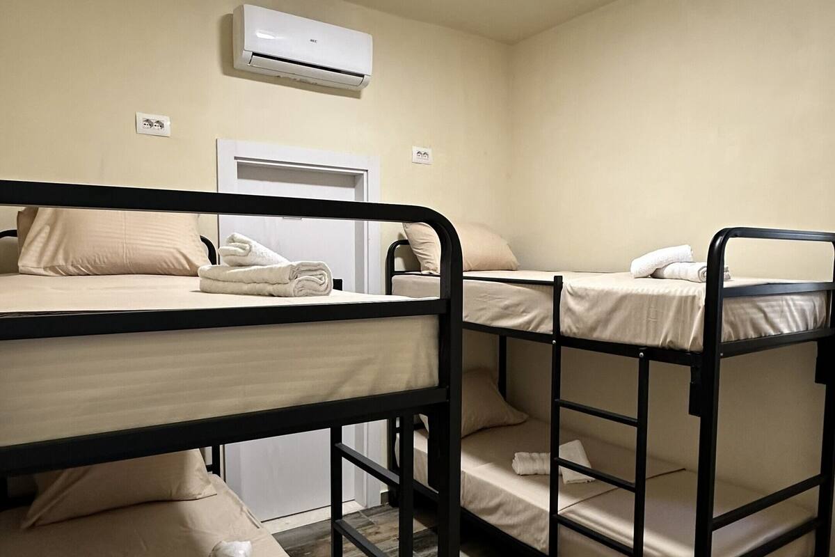 A room with bunk beds, a ceiling light, and an air conditioning unit.