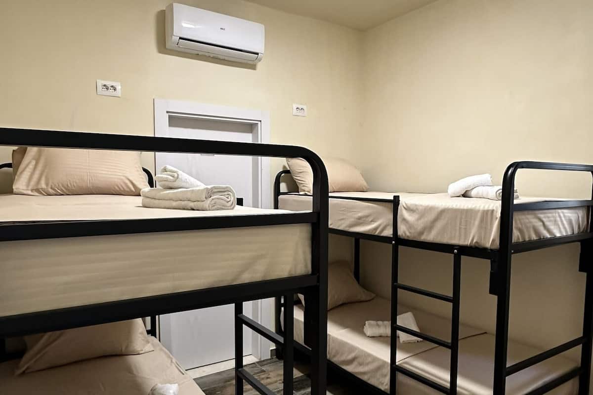 A room with bunk beds, a ceiling light, and an air conditioning unit.