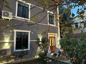 A building with multiple windows, a door, and outdoor seating.
