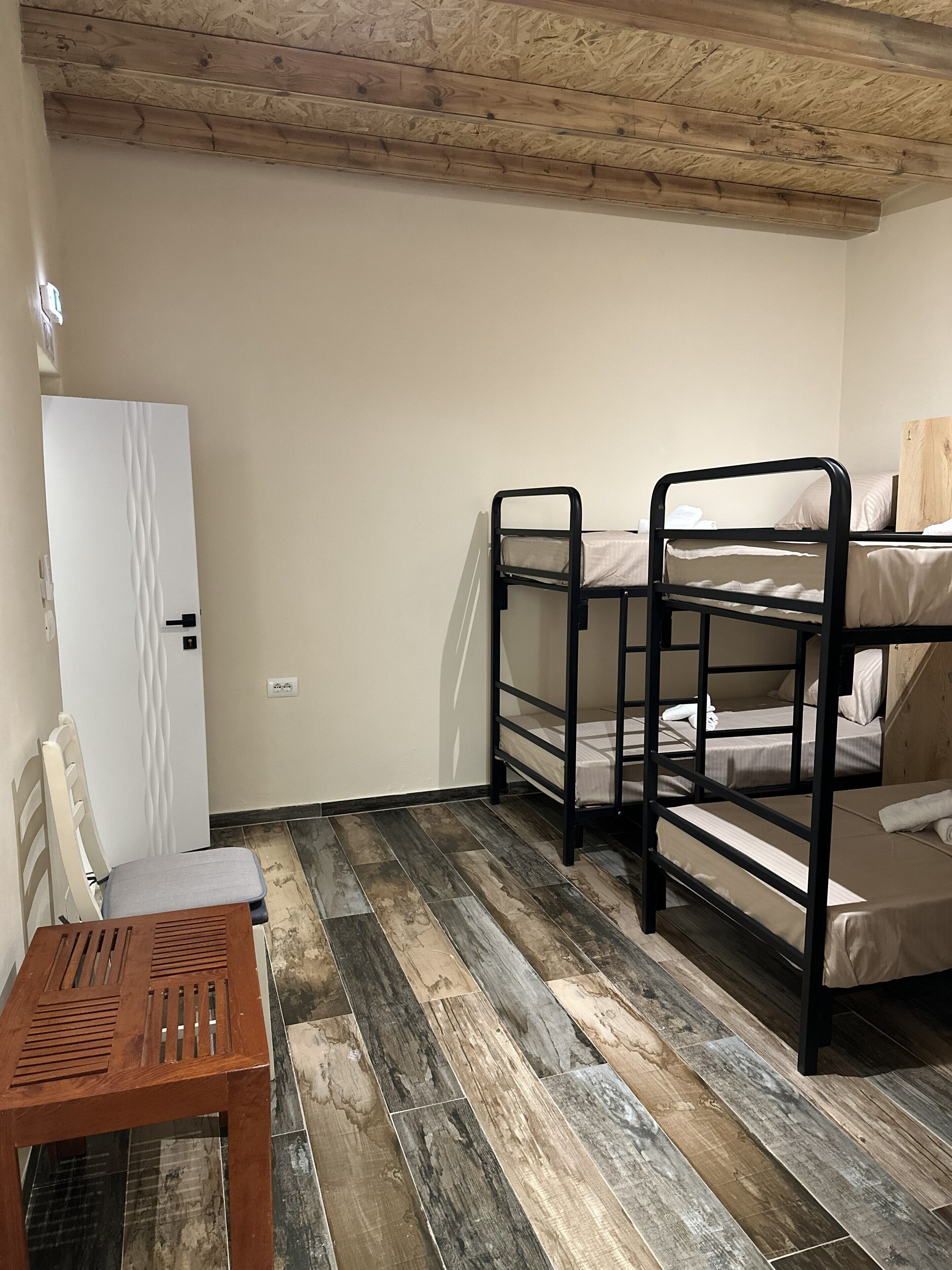 A room with bunk beds, a wooden table, and a white door.