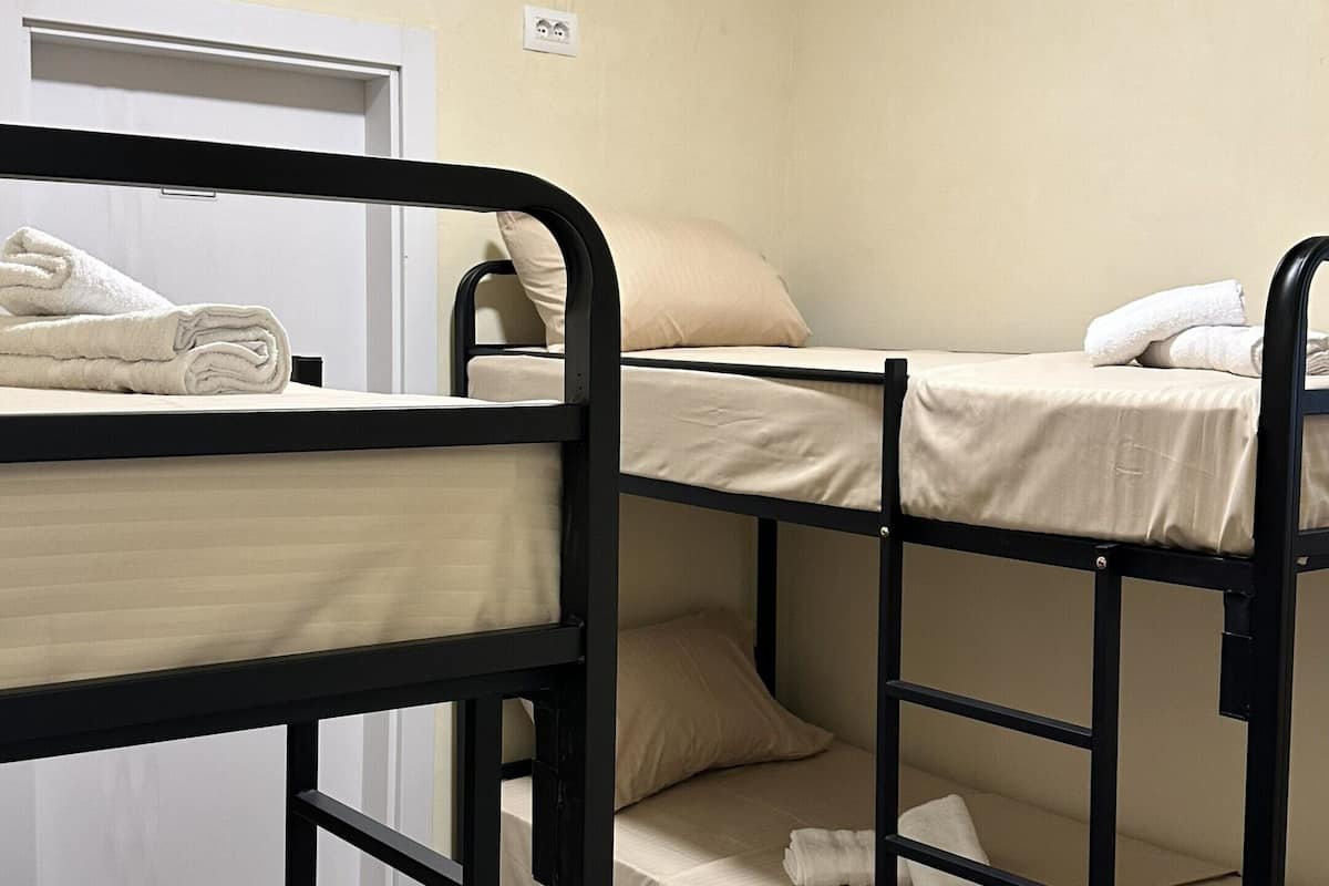 A bunk bed room with a white air conditioner, a door, and a tiled floor.