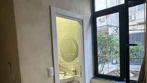 Una habitación con baño, ventana con vistas al exterior y puerta que da a otra habitación.