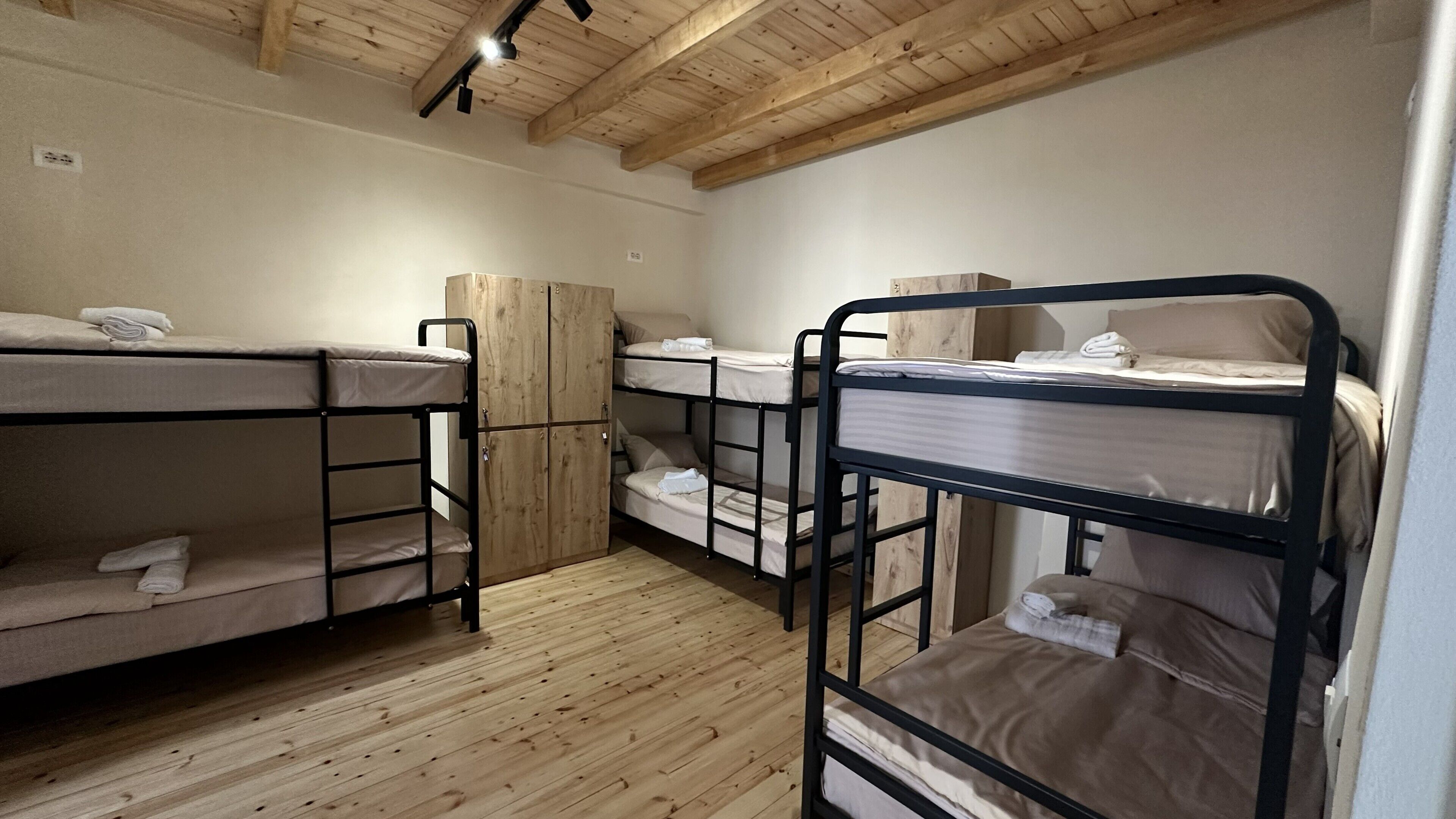 Une pièce avec des lits superposés, un plancher en bois et un plafond en bois.
