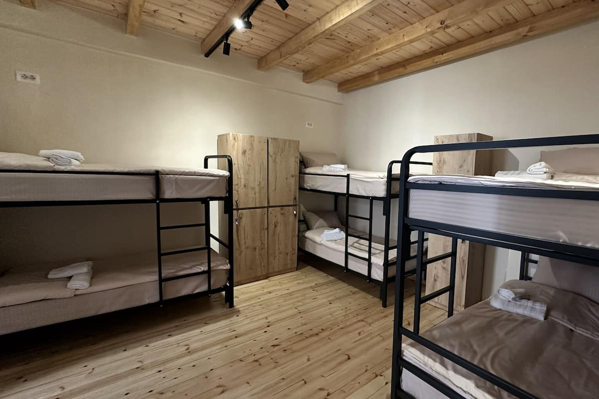 A room with bunk beds, wooden flooring, and a wooden ceiling.
