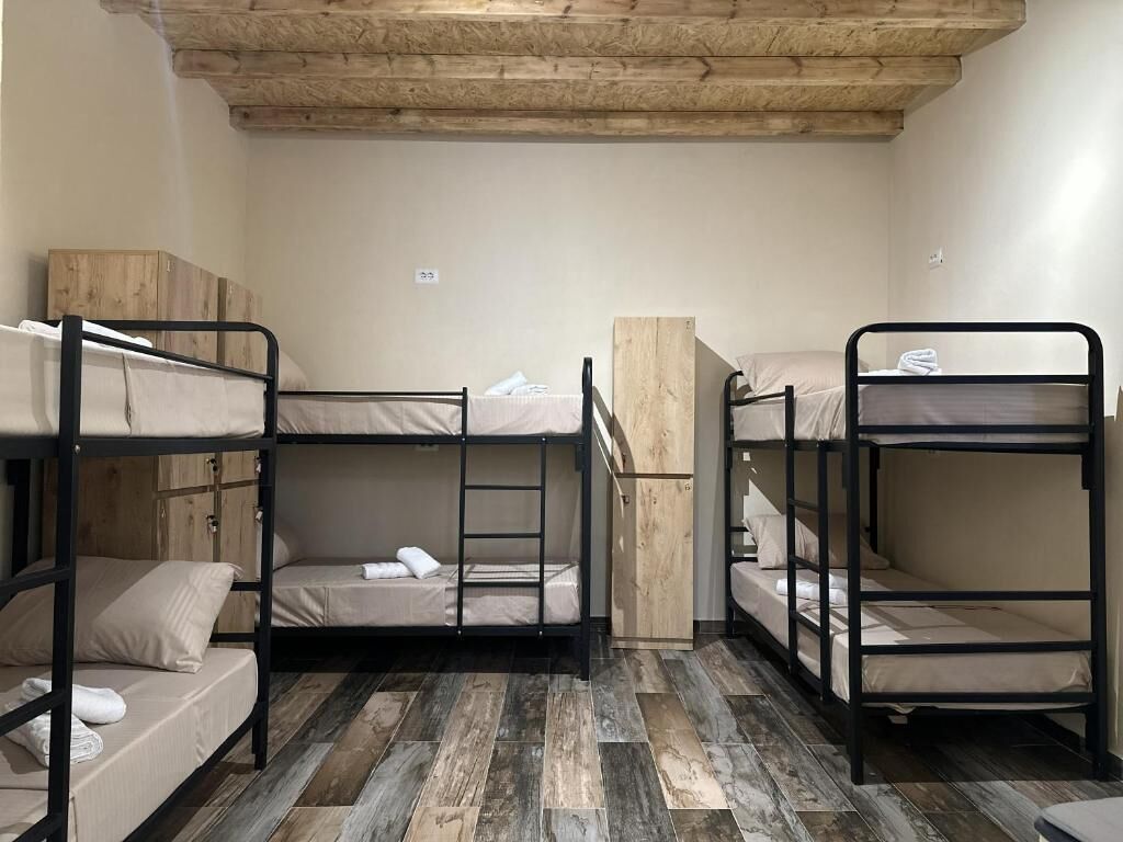 Une chambre avec des lits superposés, un plancher en bois et un aménagement simple et fonctionnel.