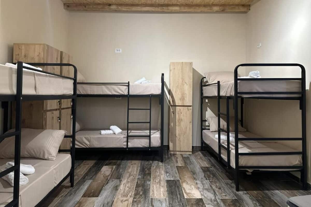 A room with bunk beds, wooden flooring, and a simple, functional design.
