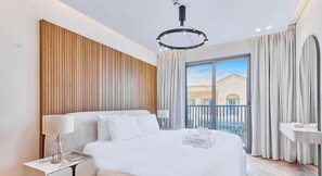 Une chambre d’hôtel moderne avec un grand lit, une table de chevet, une lampe et une vue sur l’extérieur.