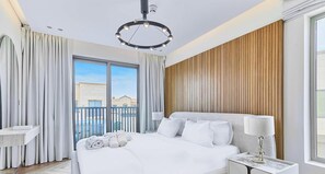 Une chambre d’hôtel avec un grand lit, une table de chevet, une lampe et une vue sur l’extérieur.