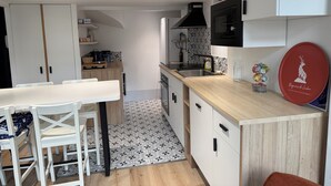Una cucina moderna con mobili bianchi, un piano di lavoro in legno e un'area pranzo con sedie bianche.