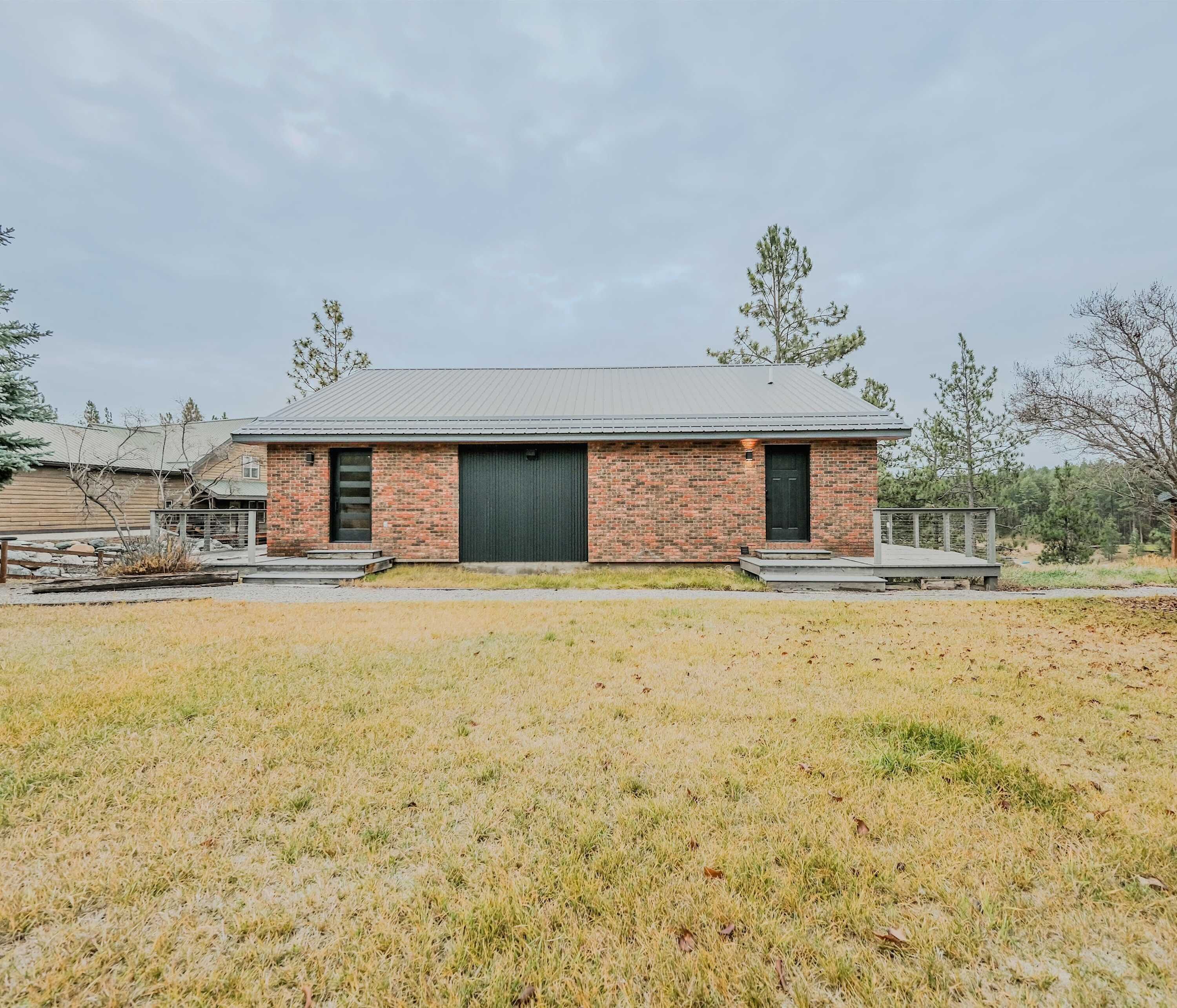 A single-story brick building with a metal roof, a front door, and a large garage door.