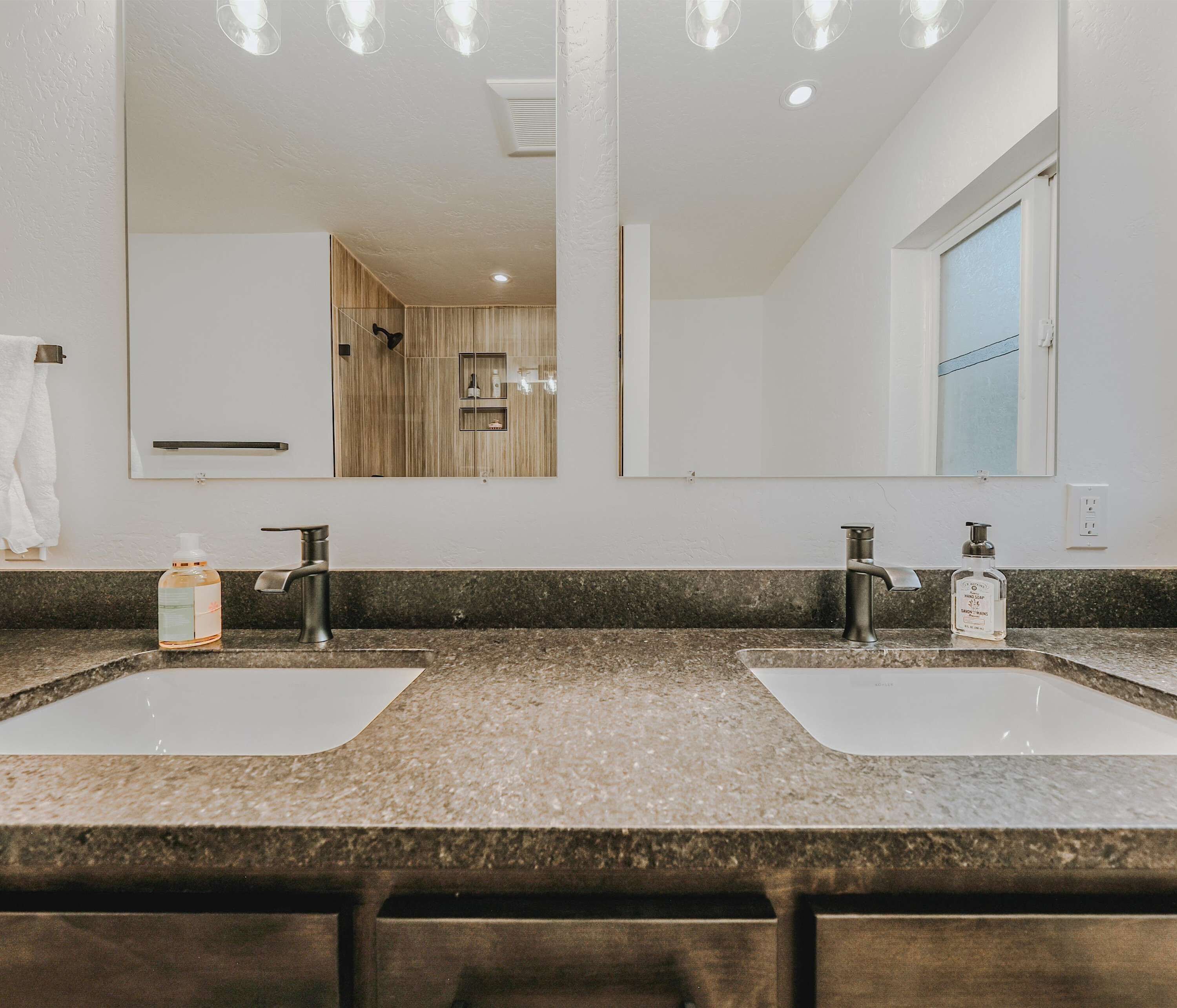 A bathroom with two sinks, a large mirror, and a window.