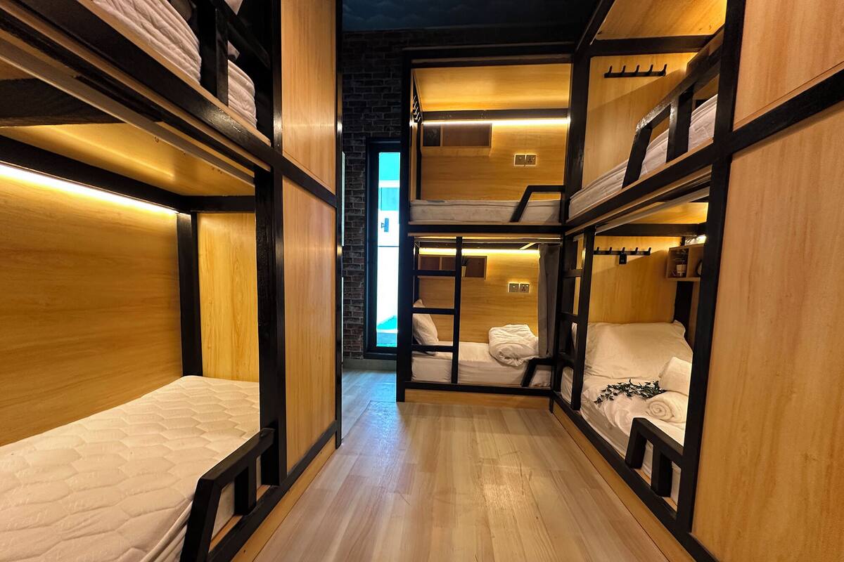 A hotel room with bunk beds, wooden flooring, and a brick wall.