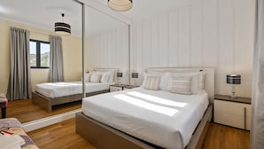 A modern hotel room with a large bed, bedside tables, a mirror, and a view of the outdoors. - Quinta do Checa by Homie (Quinta Grande)