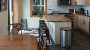 Une cuisine moderne avec un îlot central en bois, des appareils électroménagers en acier inoxydable et un grand lustre.