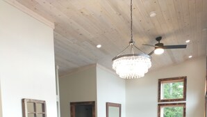 Un coin repas avec une table et des chaises en bois, un lustre et un ventilateur de plafond.