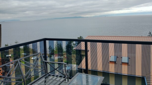 Un balcon donnant sur une vaste étendue d’eau et sur une terre lointaine.