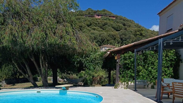 Une piscine à bord incurvé, entourée d’une terrasse carrelée.