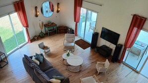 Un salon spacieux avec un grand canapé, deux fauteuils, une table basse et un téléviseur.