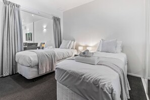A hotel room with two beds, a large mirror, and a desk with a computer.